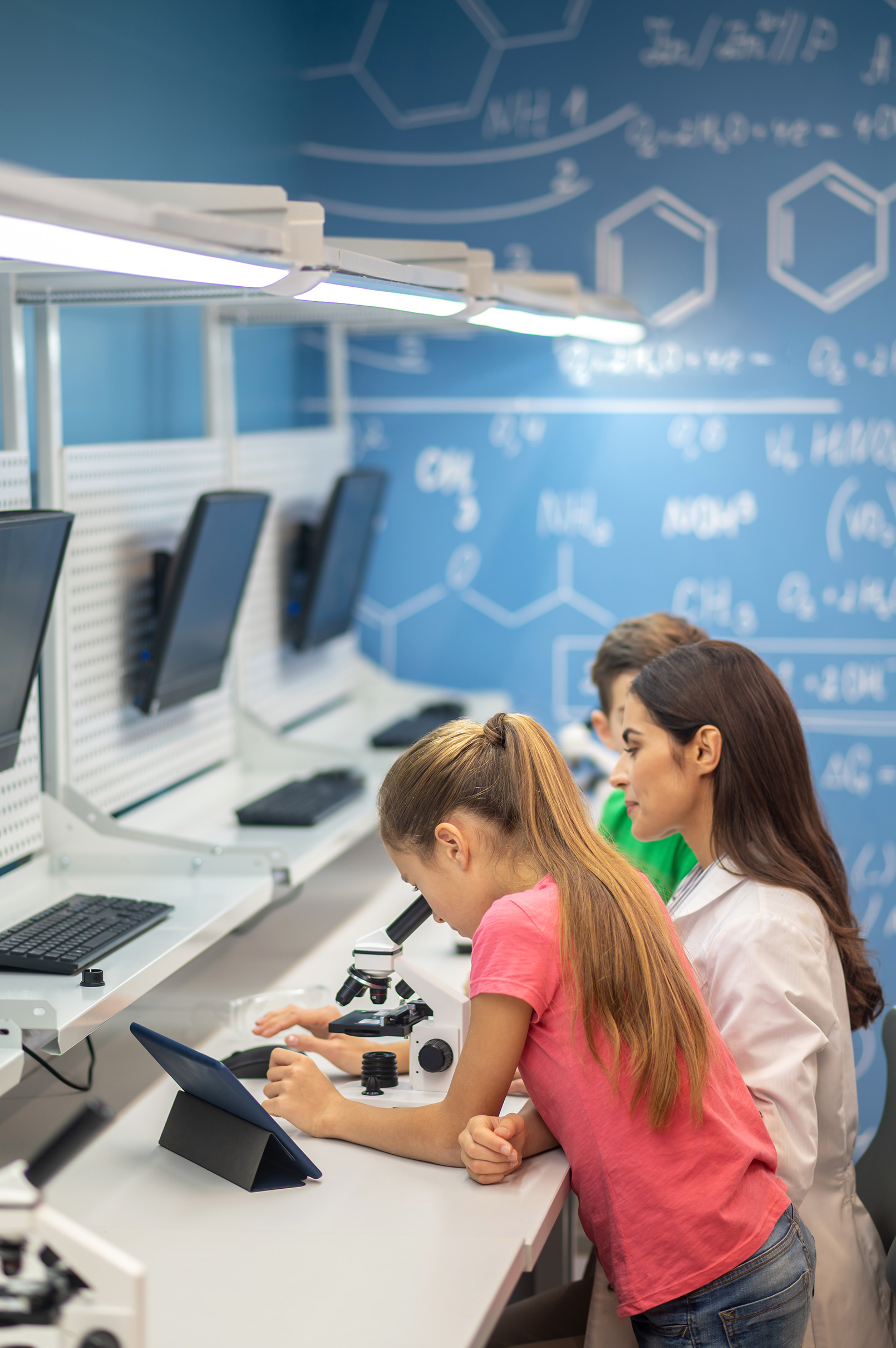 girl-near-microscope-observing-teacher